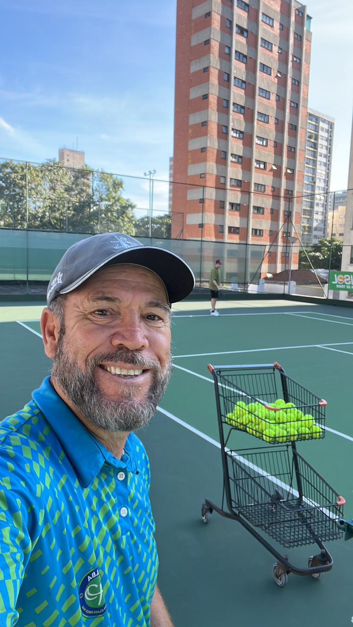 Professor em quadra com carrinho de bolas no Método Vip Tennis
